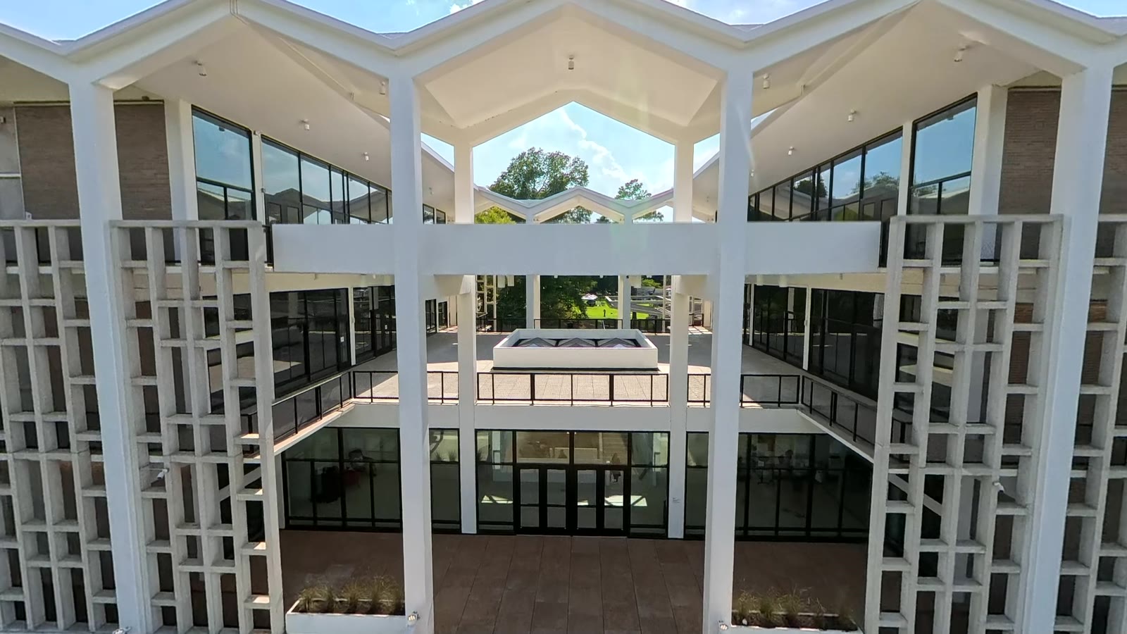 The folded roofline and concrete lattice of Rust Hall, seen from the BabaluShow drone inside the courtyard