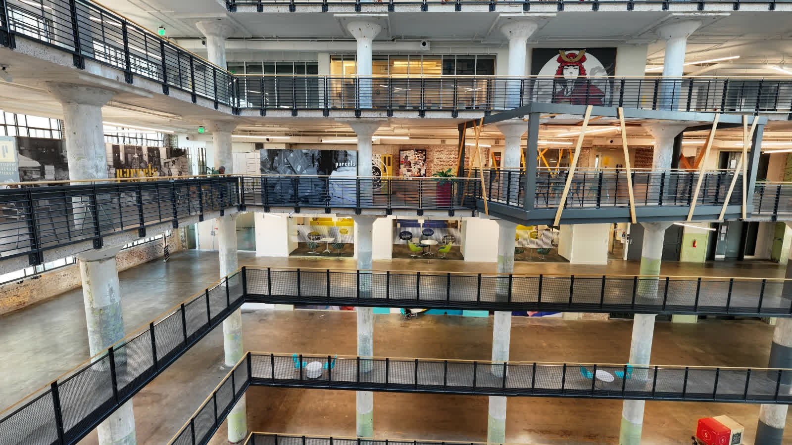 The stacked balconies, concrete columns and PARCELS sign inside the Crosstown Concourse atrium, from the BabaluShow drone